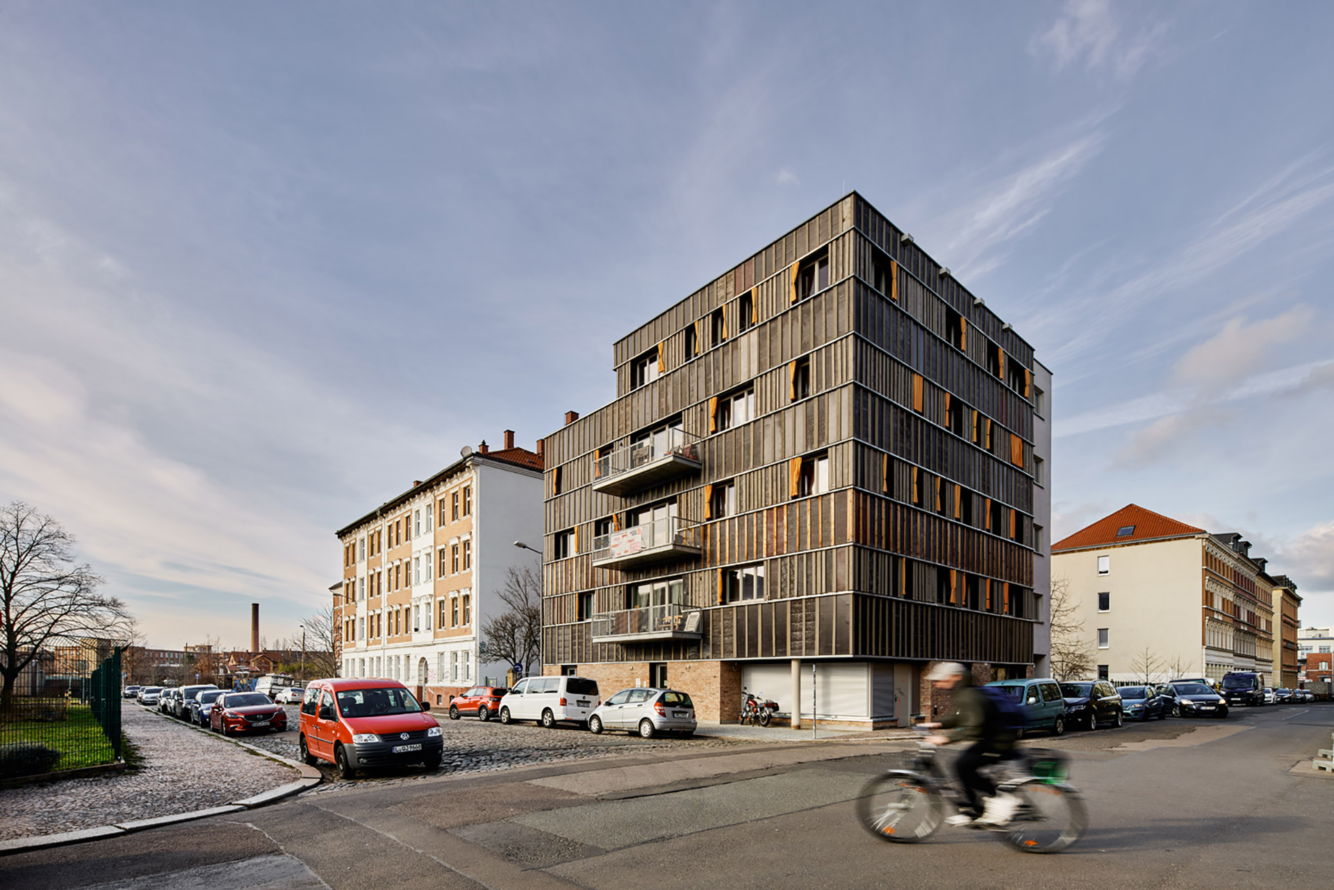 Außenaufnahme von der Straße aus zeigt das Gebäude über Eck mit dessen Fassade aus recycelten Materialien.