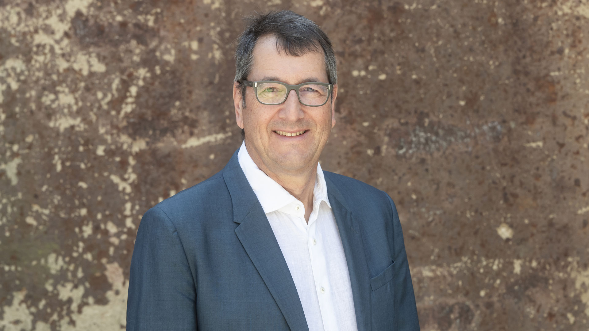 Das Foto zeigt ein Portrait von Hilmar von Lojewski vor einer braunen Wand.