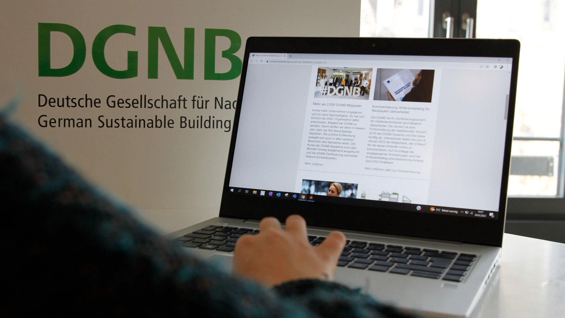 DGNB Newsletter auf Laptop auf einem weißen Stehtisch mit DGNB Logo im Hintergrund