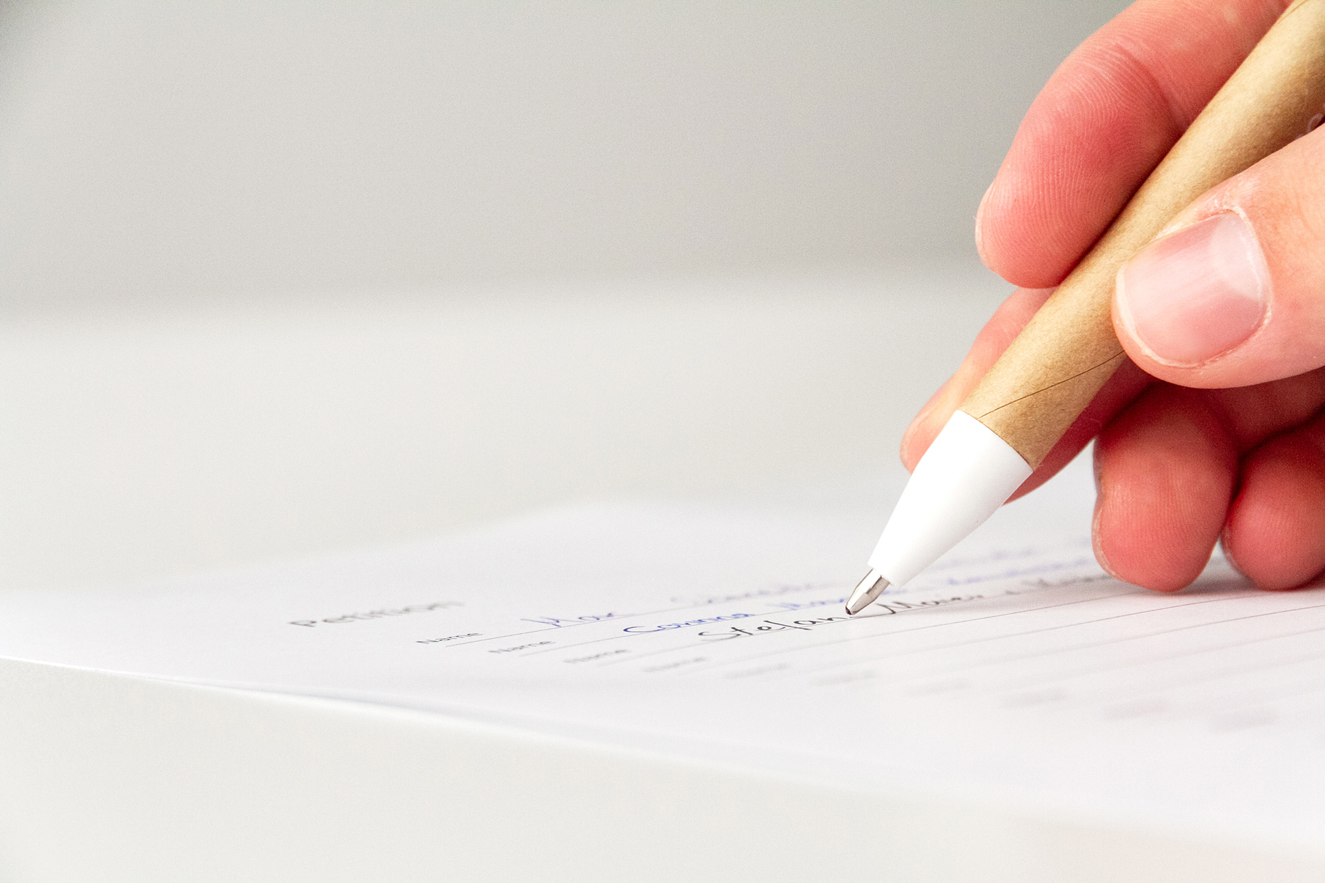 Hand, die mit einem Stift auf Papier schreibt