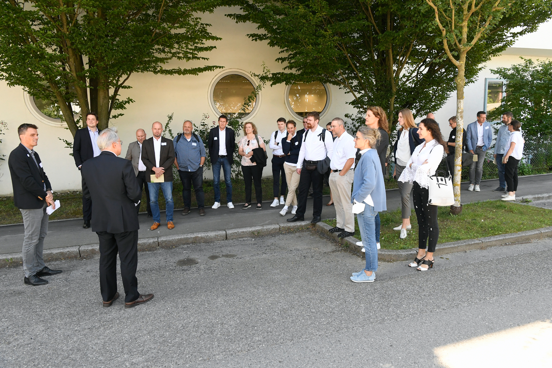 Menschengruppe bei draußen, die einer referierenden Person zuhört