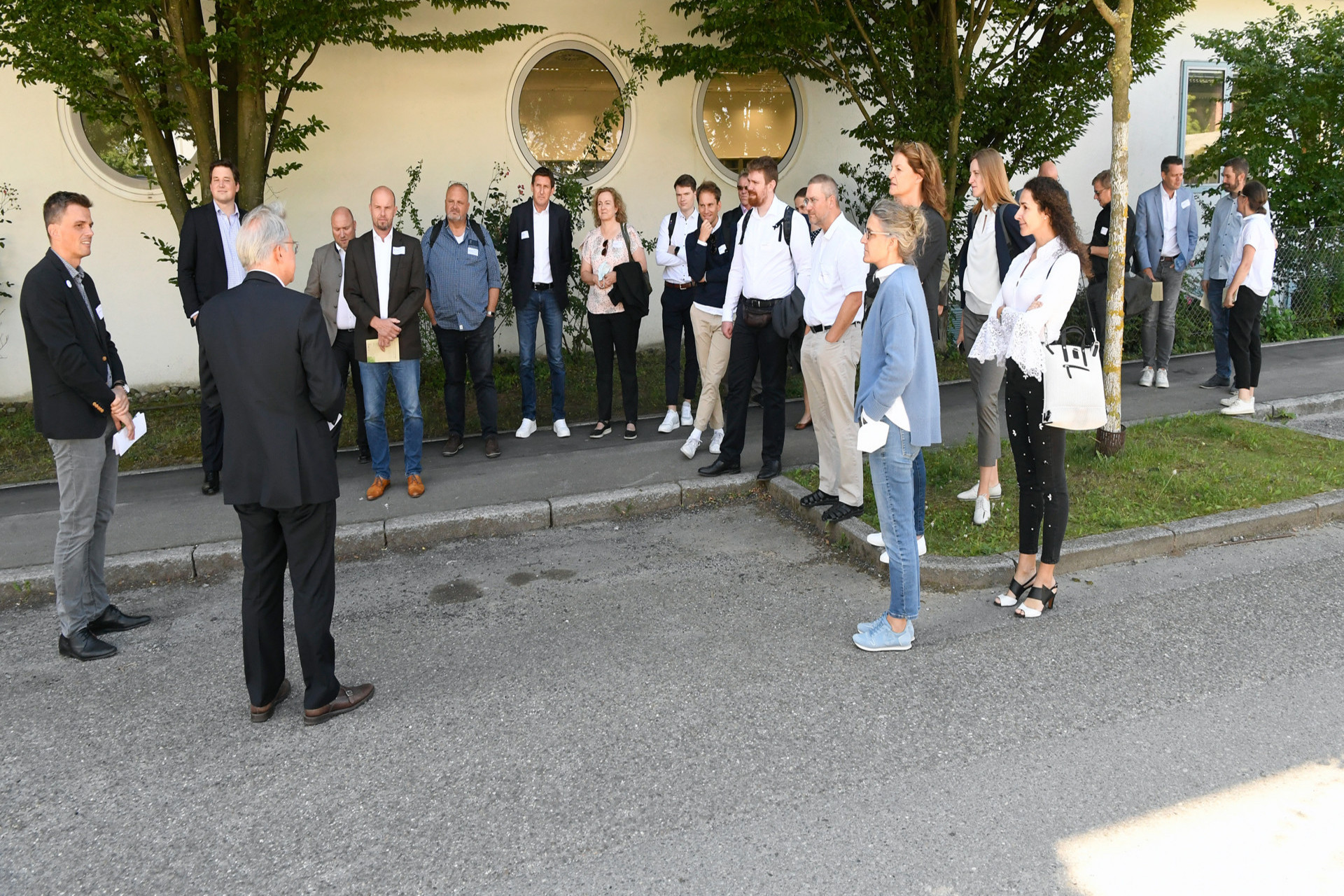 Menschengruppe bei draußen, die einer referierenden Person zuhört