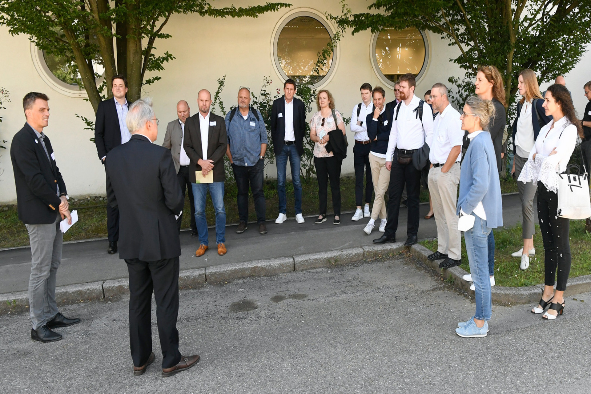 Menschengruppe bei draußen, die einer referierenden Person zuhört