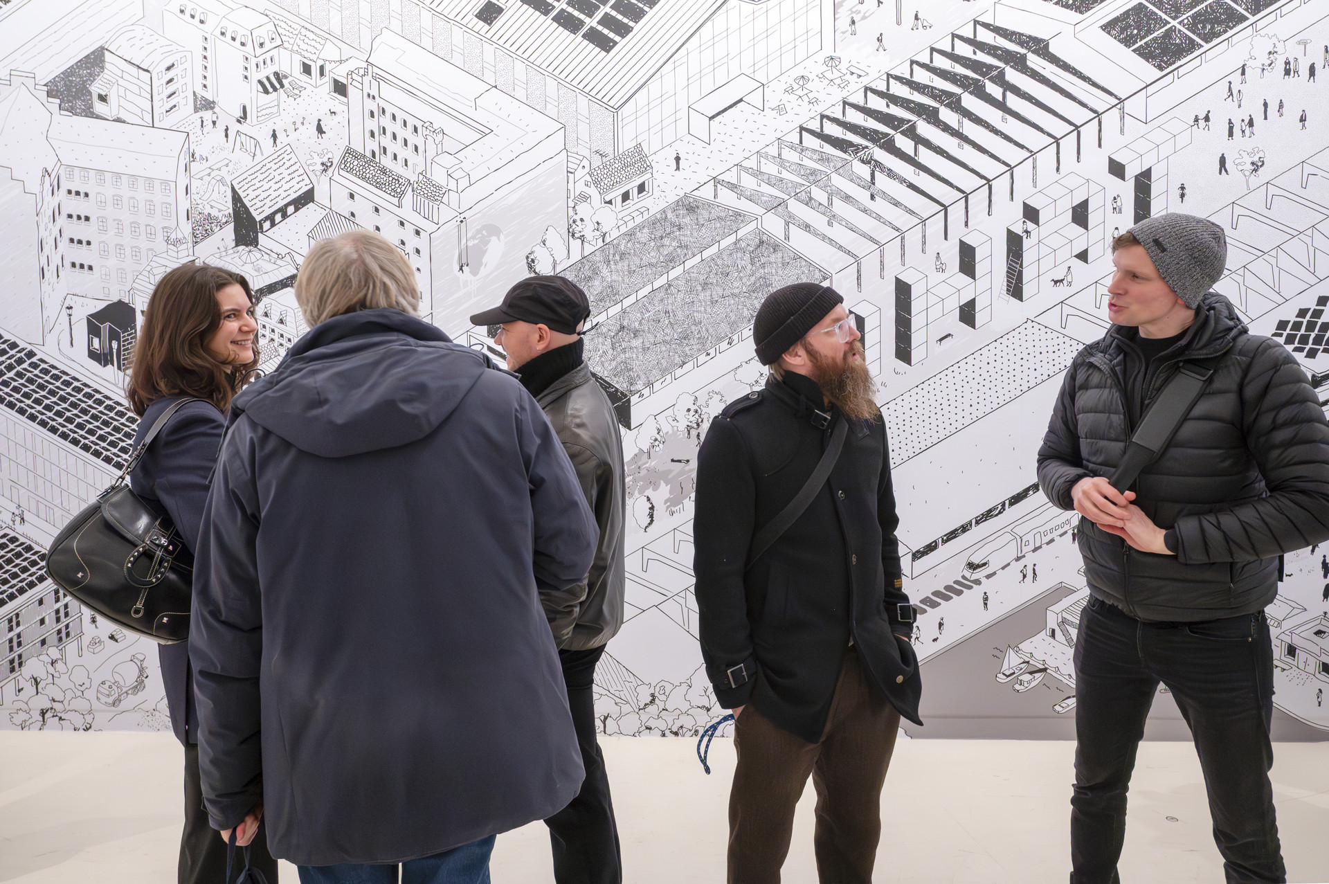 Foto von 5 Menschen in der DGNB Ausstellung vor dem Wimmelwandbild.