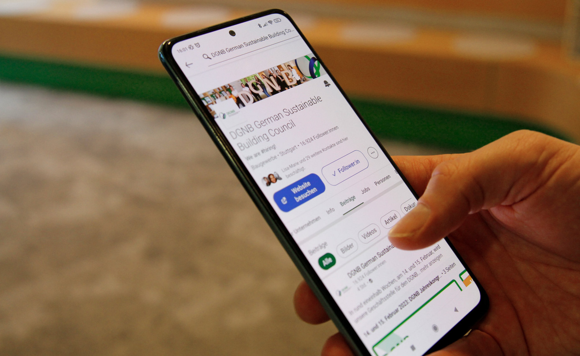 Foto von einem Smartphone, auf welchem der LinkedIn-Account der DGNB zu sehen ist.