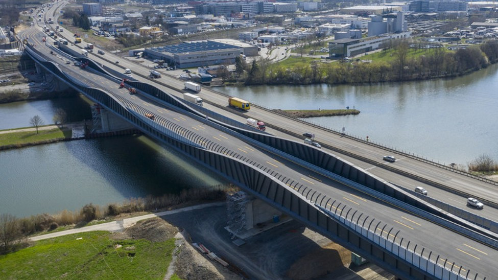 Projektfoto. Zu sehen ist ein Foto aus der Luft von einem mehrspurigen, befahrenen Straßenabschnitt, der über ein Gewässer führt. 